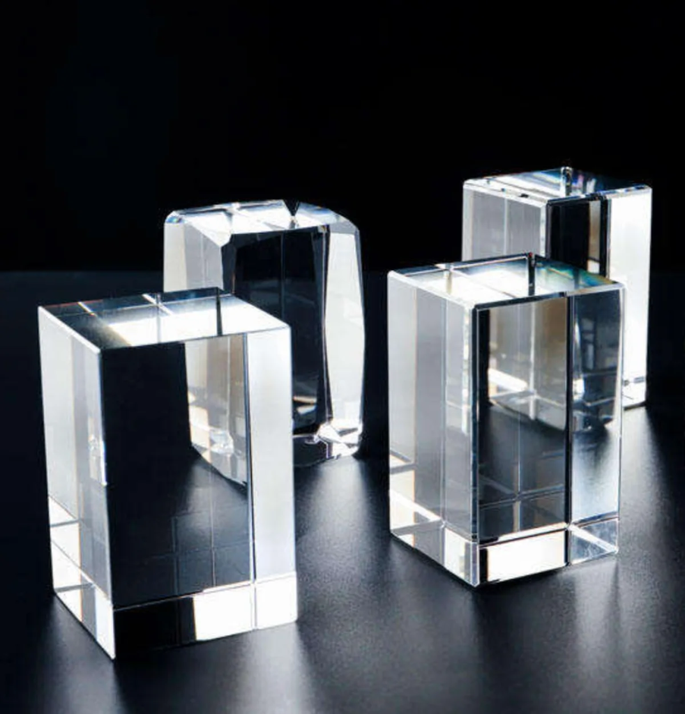 Group of clear K9 optical crystal blocks in different sizes on a black background